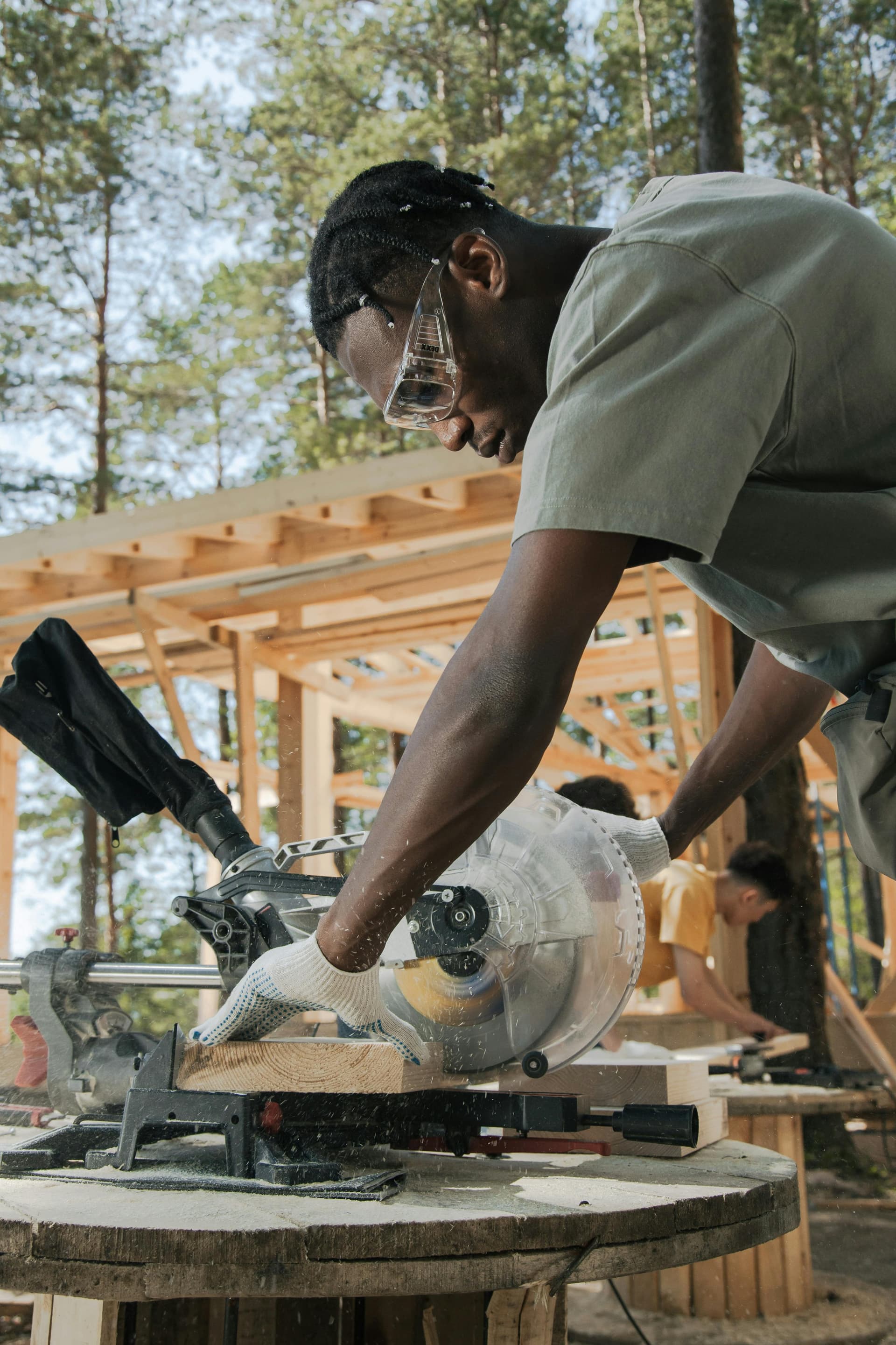 Tradesperson cutting wood with a miter saw on a job site