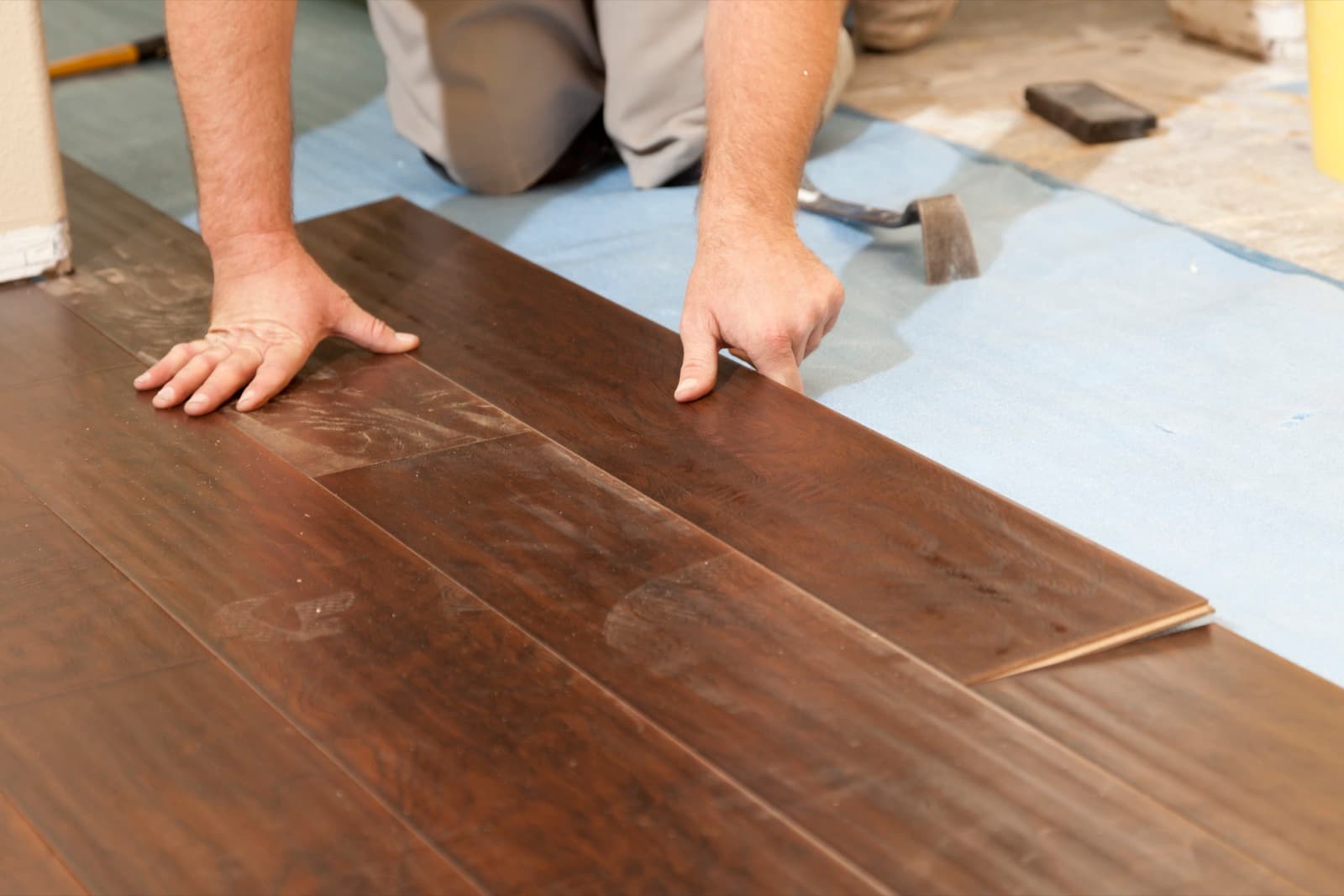 Flooring installer laying hardwood planks in a residential room